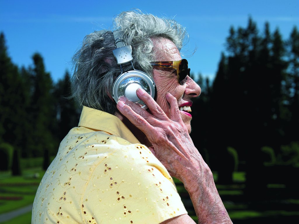 elderly woman listening to headphones. exterior day park setting