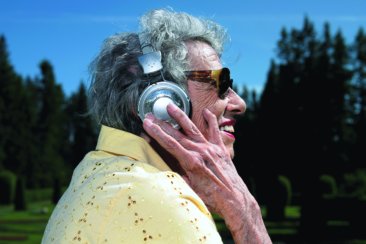elderly woman listening to headphones. exterior day park setting