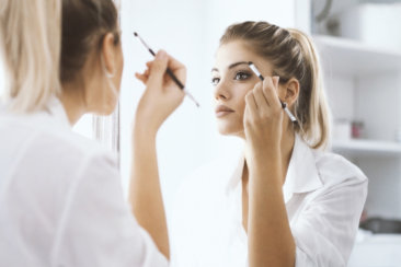 femme qui se regarde dans un miroir et se maquille