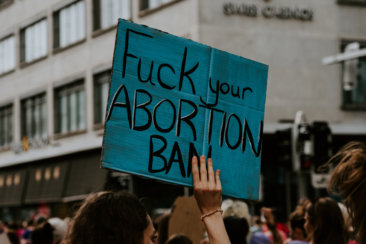 person holding fuck your abortion ban printed banner