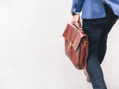 person walking holding brown leather bag
