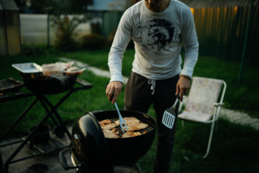 person in white long sleeve shirt holding black pan with food