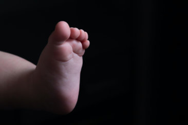 persons hand holding babys foot