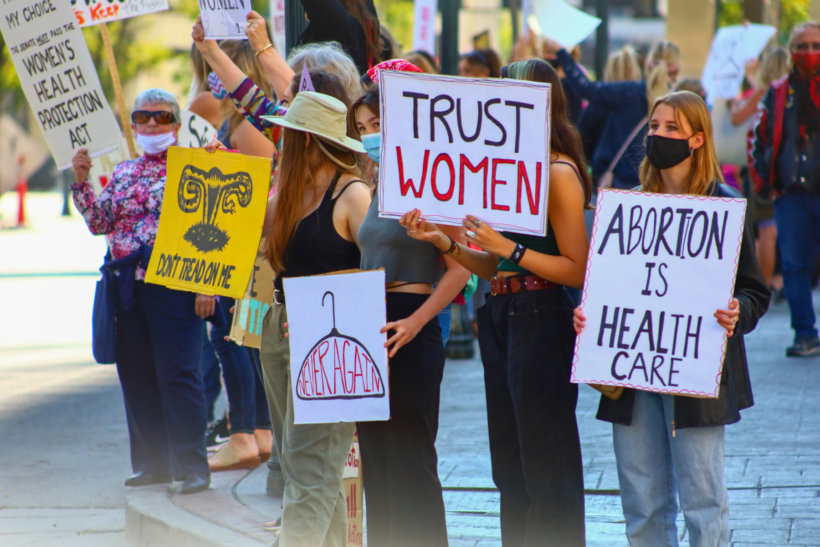 a group of women holding signs and wearing masks