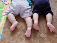 baby in white shirt and black pants lying on brown carpet