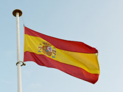 the spanish flag is flying high in the sky