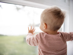child in red and white striped shirt looking out the window